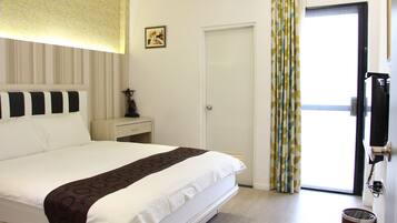 Habitación de hotel con cama, mesita de noche, lámpara, un cuadro en la pared, una puerta y ventana con cortinas.