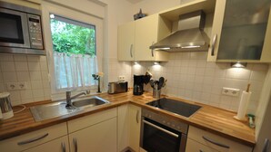 A kitchen with white cabinets, a stainless steel sink, a toaster, and an oven. - No. 39 - Cottage At the marina (Wittmund)