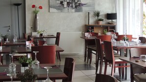 A restaurant with multiple tables and chairs, a large abstract painting on the wall, and potted plants. - Auberge Denena Logis (Aicirits-Camou-Suhast)