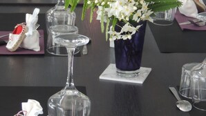 A long dining table set with purple placemats, clear glassware, and decorative items including flowers and figurines. - Auberge Denena Logis (Aicirits-Camou-Suhast)
