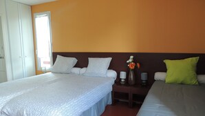 A hotel room with two beds, a nightstand with a vase of flowers, and a window with curtains. - Auberge Denena Logis (Aicirits-Camou-Suhast)