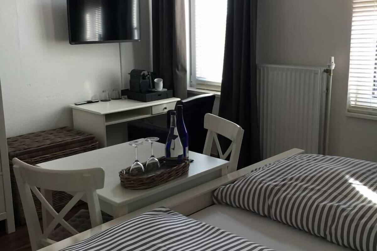 Hotellihuone, jossa on sänky, työpöytä tuolilla, seinälle asennettu televisio ja ikkuna, jossa on verhot.