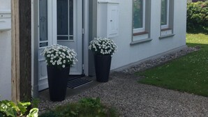 Un edificio blanco con una puerta, dos ventanas y una placa en la pared.