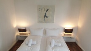 Habitación de hotel con una cama grande, dos mesitas de noche con lámparas y una obra de arte colgada en la pared.
