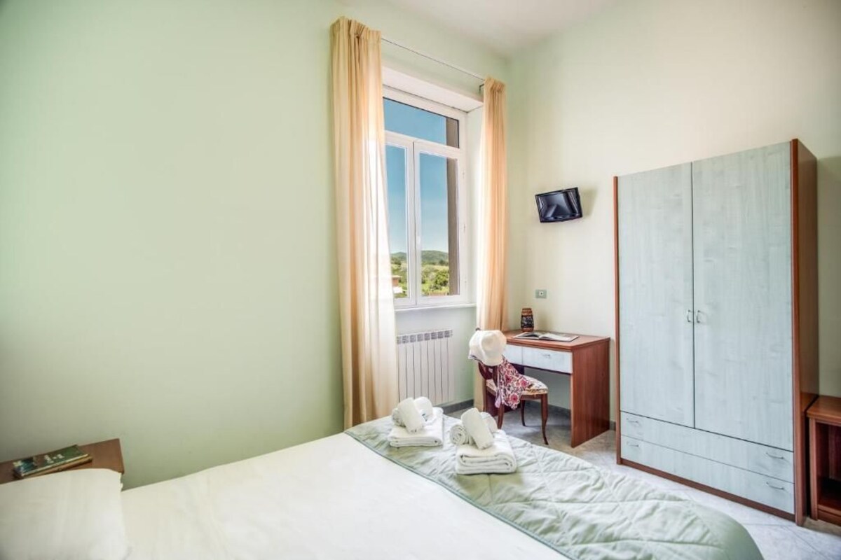 Un dormitorio con cama, escritorio, silla, armario y televisor.