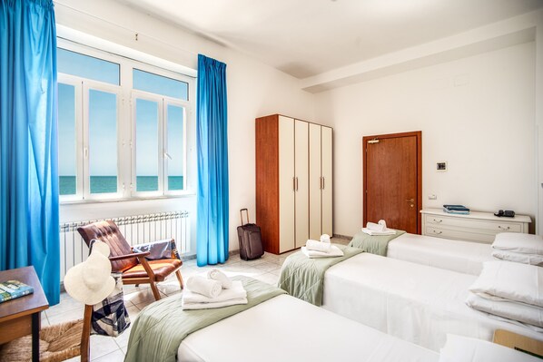 A hotel room with two beds, a wardrobe, a desk, and a chair.