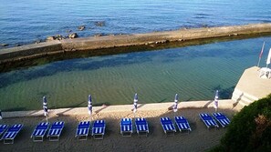 Praia particular, areia branca, espreguiçadeiras, guarda-sóis 