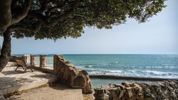 A stone bench and railing by a rocky seaside. - Villa MG Hotel (Santa Marinella)
