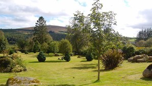 Un jardin bien entretenu, agrémenté de divers arbres et arbustes, d’une pelouse verdoyante et de gros rochers.