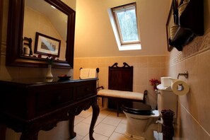 Et badeværelse med en trævask, et spejl, et toilet og et vindue.