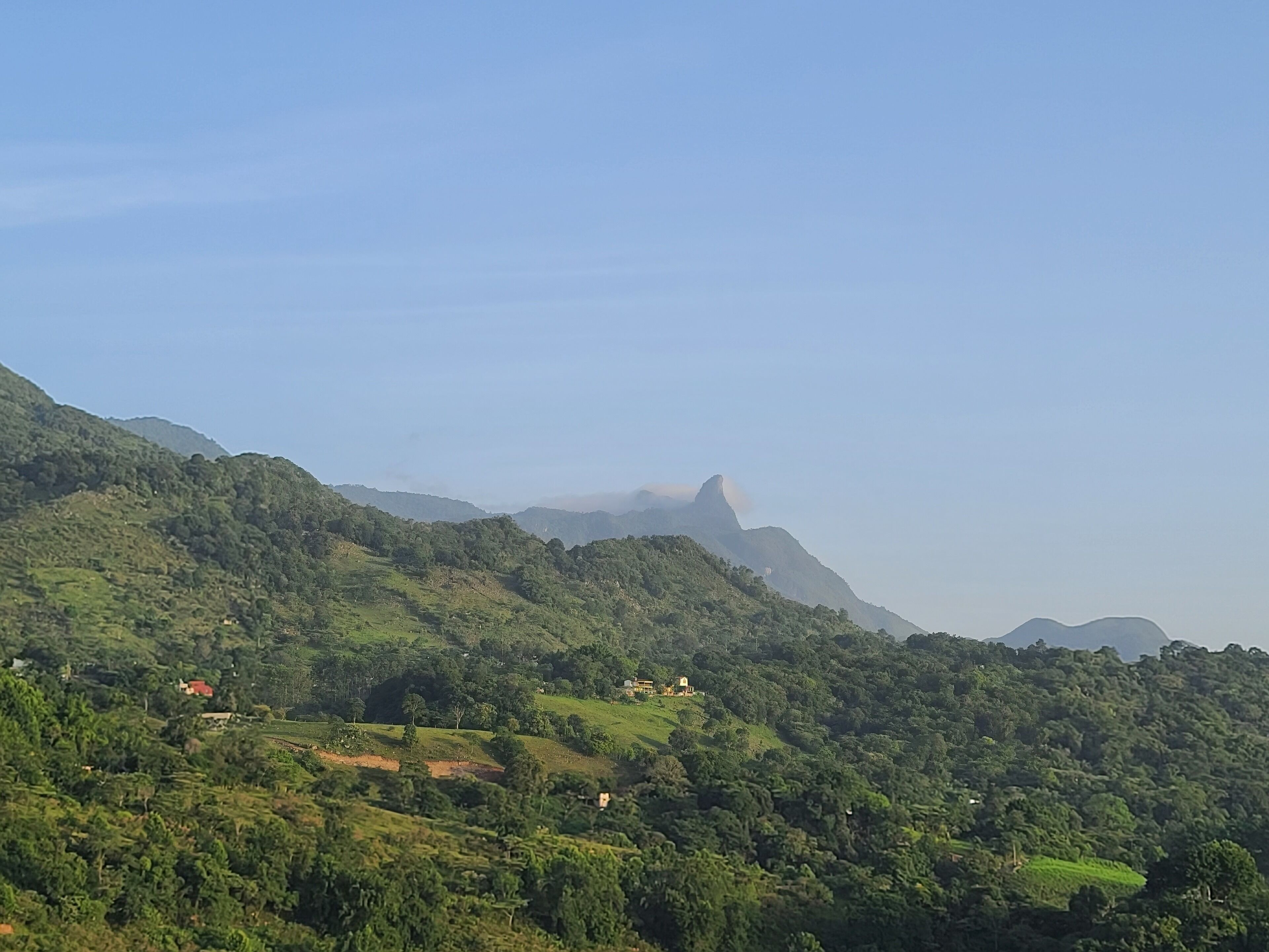A mountainous landscape with lush greenery and scattered buildings.