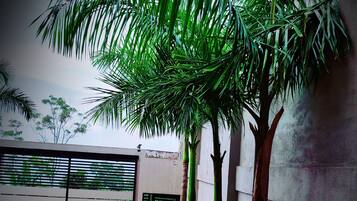 Un balcón con vista a un patio, que incluye una sombrilla azul y mobiliario de exterior.