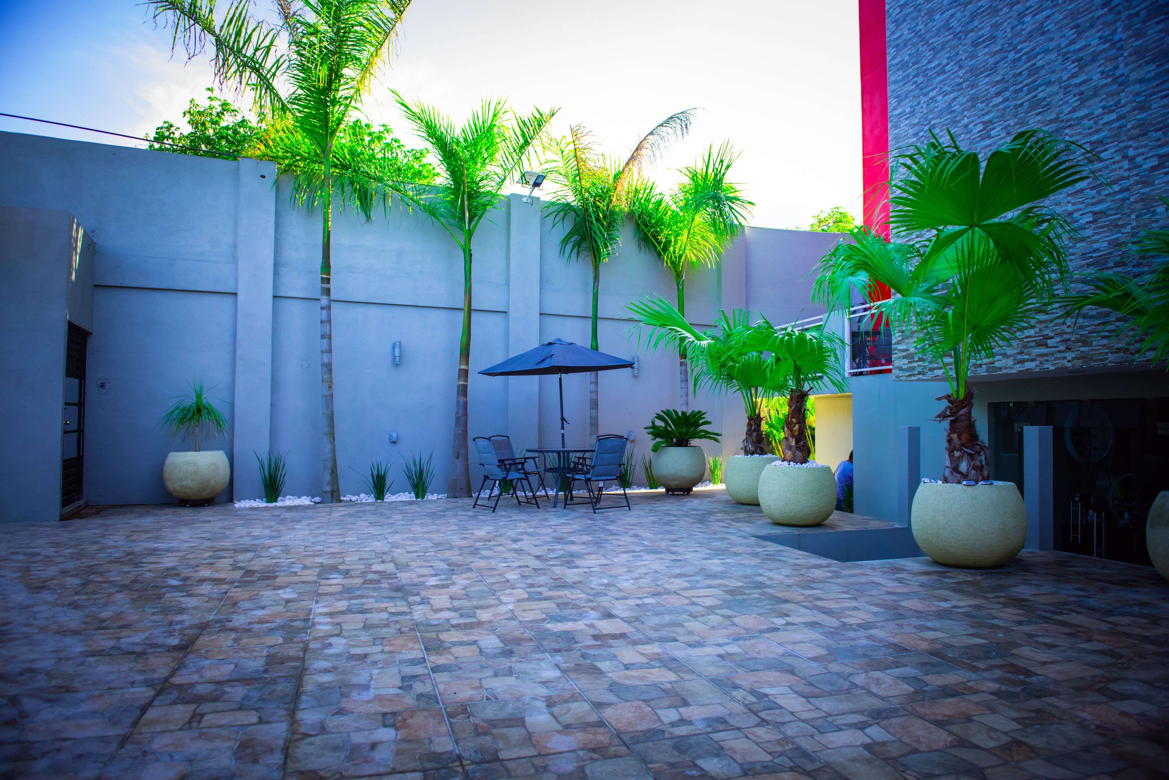 A courtyard with a tiled floor, a table with chairs, and potted plants.