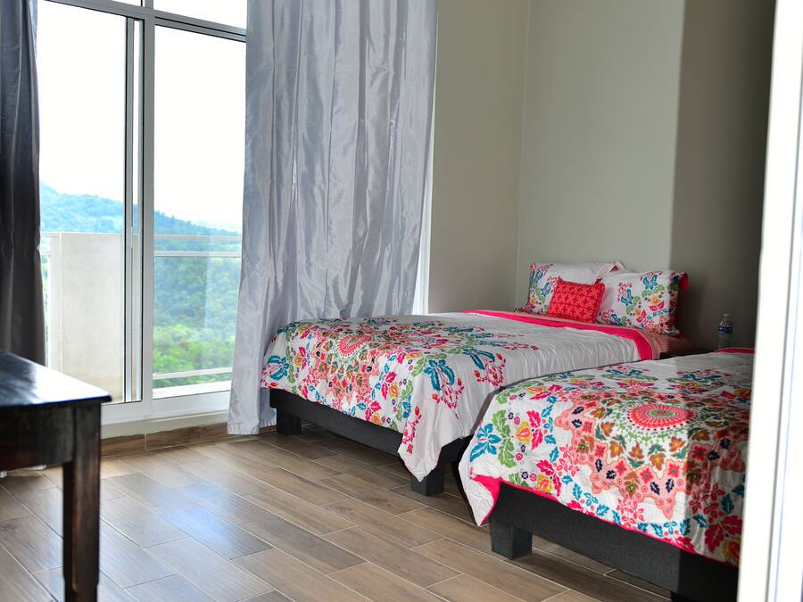Un dormitorio con dos camas, un ventanal y vistas al exterior.