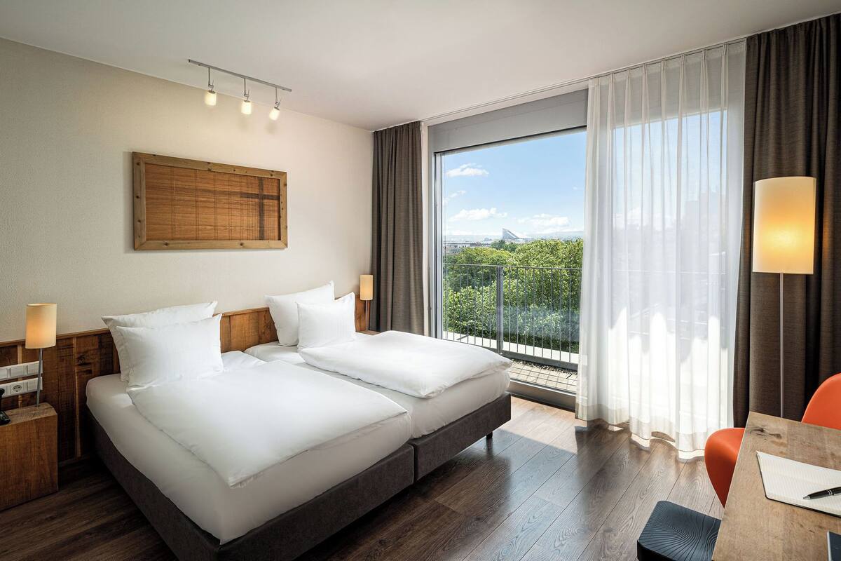 Una habitación de hotel con una cama grande, un escritorio y vistas a la ciudad.