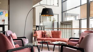 Un salon moderne comprenant un canapé, des fauteuils, une table basse et un lampadaire.
