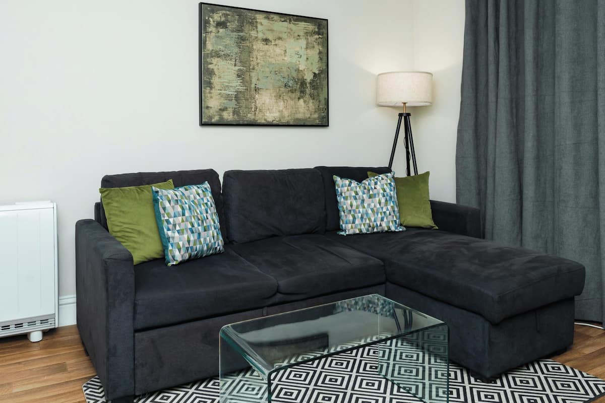 A modern living room with a sectional sofa, a glass coffee table, and a patterned rug.