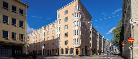 Un edificio de varios pisos con entrada en esquina, ventanas amplias y un paso de peatones.