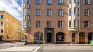 Un edificio de varios pisos con entrada en esquina, ventanas amplias y un paso de peatones.