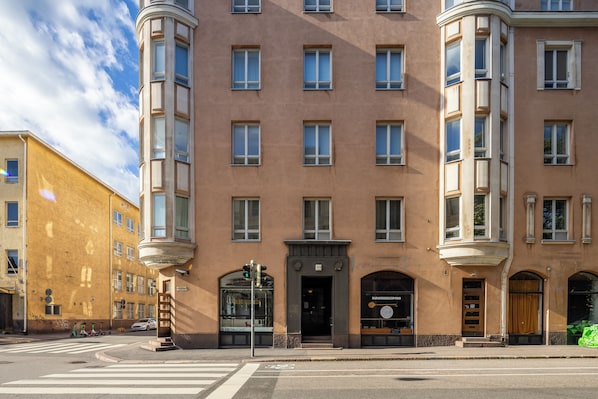 A multi-story building with a corner entrance, large windows, and a pedestrian crossing.