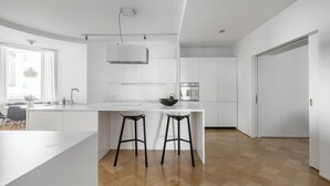 Una cocina moderna con armarios blancos, una isla central con taburetes y un horno empotrado.
