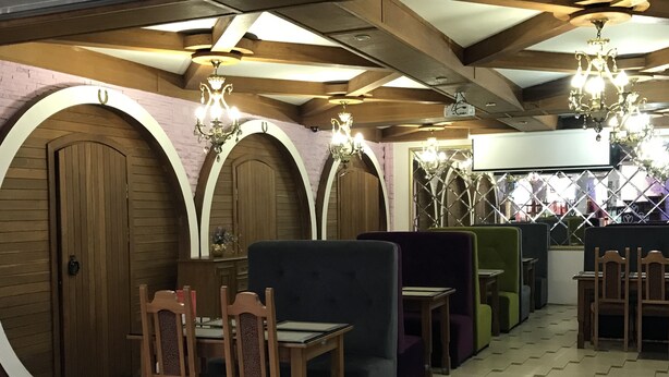 Un interior de restaurante con paneles de madera, arcos y suelo de baldosas.