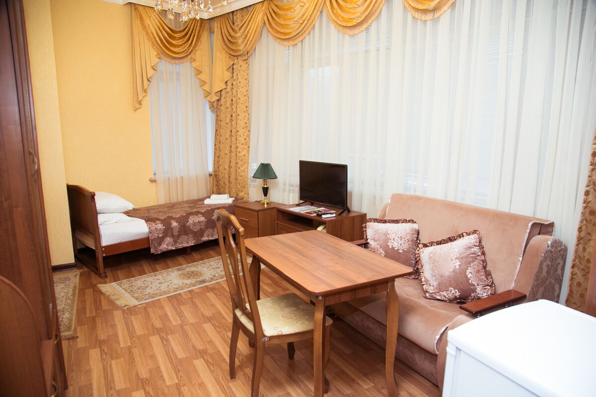 Una habitación de hotel con una cama y una mesa de madera, un sofá y un televisor.