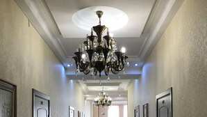 Un pasillo con candelabro, puertas y alfombra estampada.