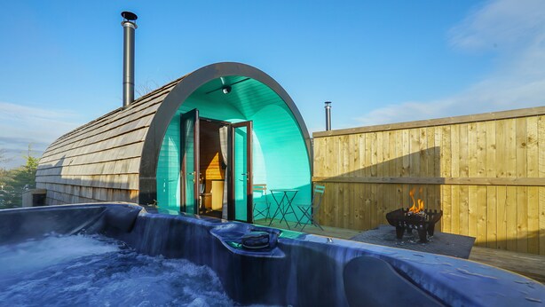 A hot tub area with a wooden deck and a wooden fence. - Cheshire Glamping Pods (Frodsham)