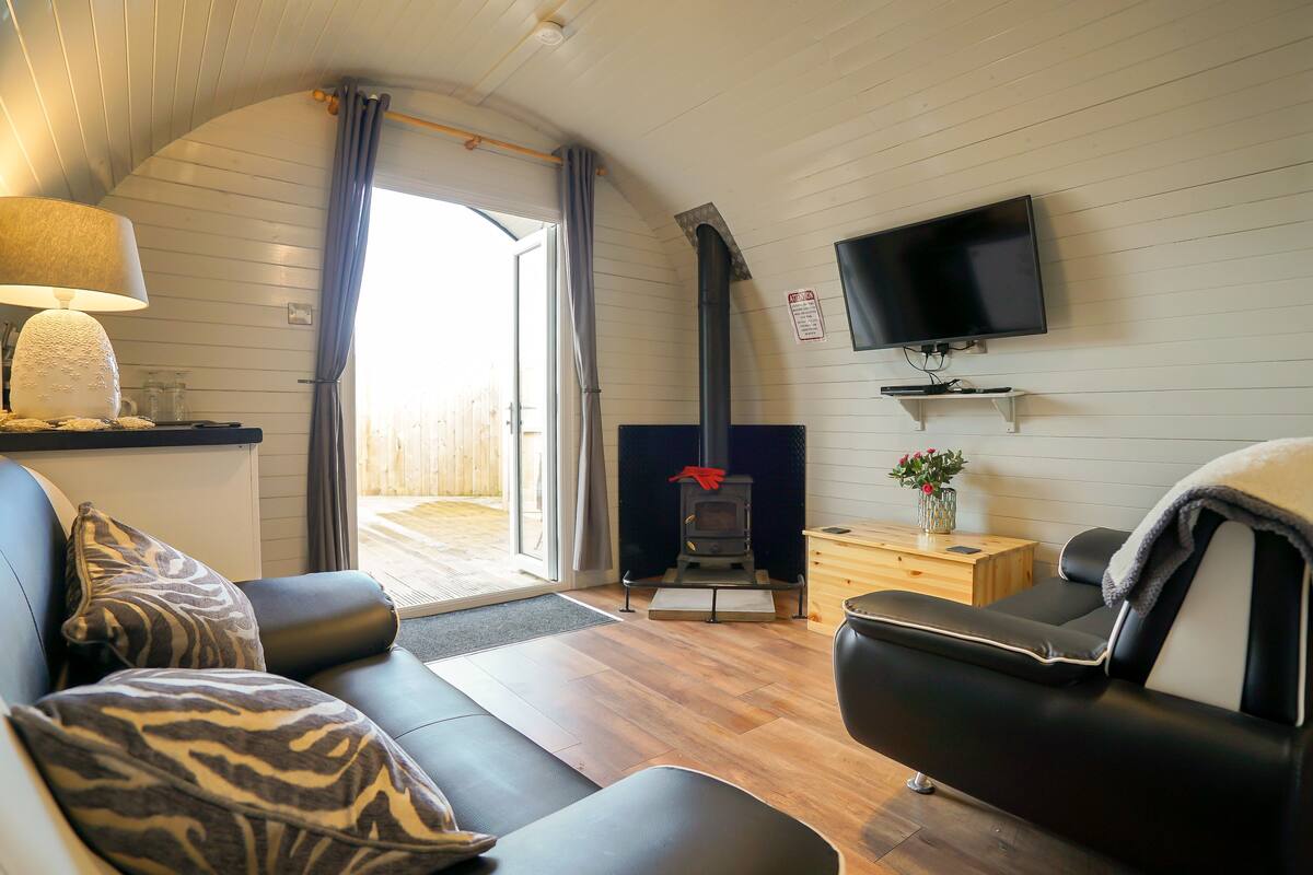 A cozy living room with a sofa, a television mounted on the wall, and a fireplace.