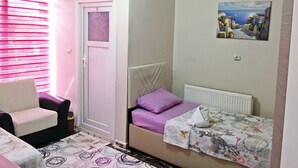 Una habitación con cama, una silla, un radiador y un cuadro en la pared.