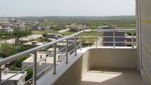Un balcón con vistas a una zona residencial, con edificios y zonas verdes.