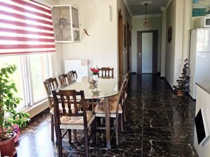 A dining area with a glass table, wooden chairs, and a vase with flowers.
