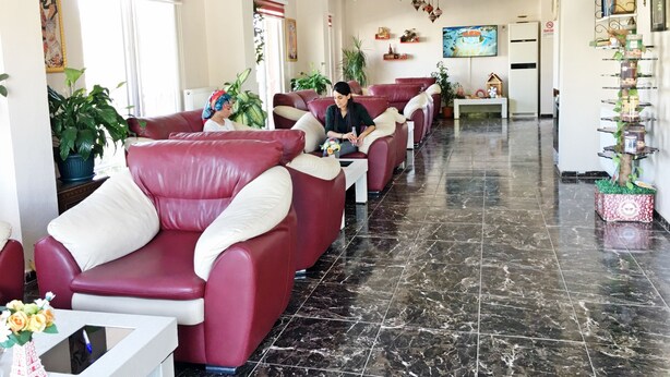 Un vestíbulo de hotel con sofás de cuero, piso de mármol y una pantalla de televisión.