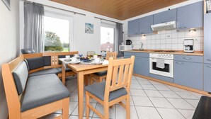 Una cocina moderna con armarios azules, un comedor con mobiliario de madera y vistas al exterior.