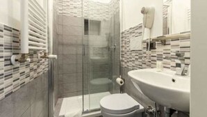 Un baño moderno con ducha de vidrio, lavamanos blanco y salpicadero de azulejos.