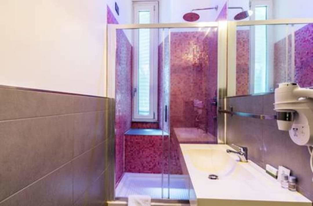 Un bagno moderno con box doccia in vetro, lavandino e specchio.