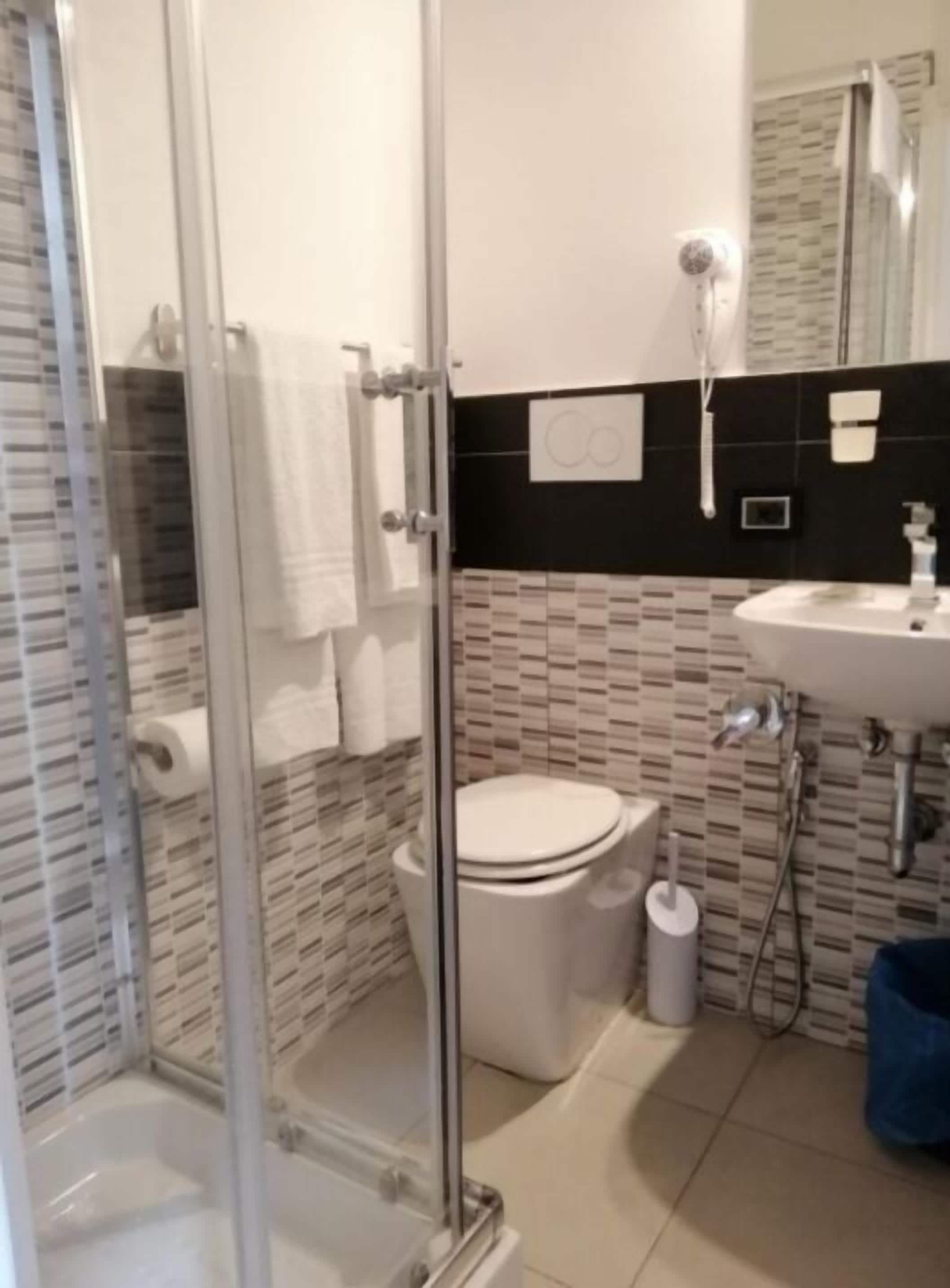 A bathroom with a glass shower enclosure, a toilet, a sink, and a tiled backsplash.