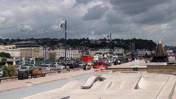 A skate park with ramps and benches, surrounded by buildings and parked cars.