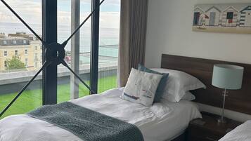 Habitación de hotel con un ventanal grande que ofrece vistas a la ciudad y al mar.
