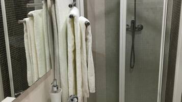 Een badkamer met een witte wastafel, een douchecabine van glas en een spiegel.