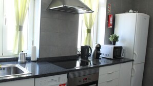 A modern kitchen with a stainless steel range hood, a built-in dishwasher, a microwave, and a refrigerator. - Aveiro White House (Aveiro)