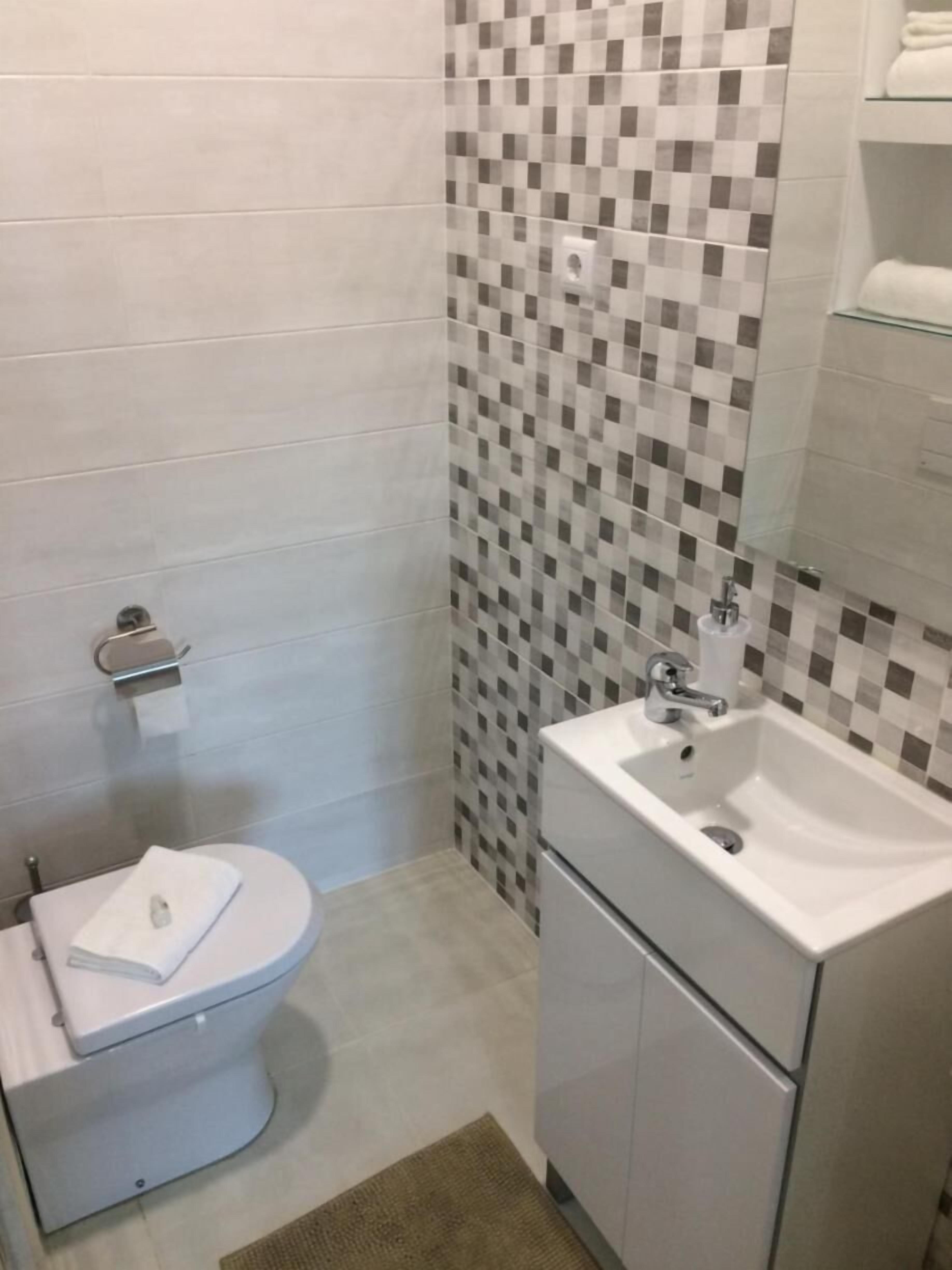 Ein modernes Badezimmer mit Toilette, Waschbecken und gefliesten Wänden.