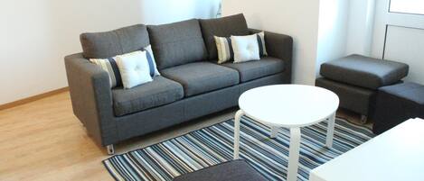 Una sala de estar moderna con un sofá gris, una mesa de centro blanca y una alfombra a rayas.