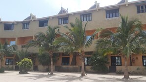 Un immeuble à plusieurs étages doté d’une cour intérieure bordée de palmiers.