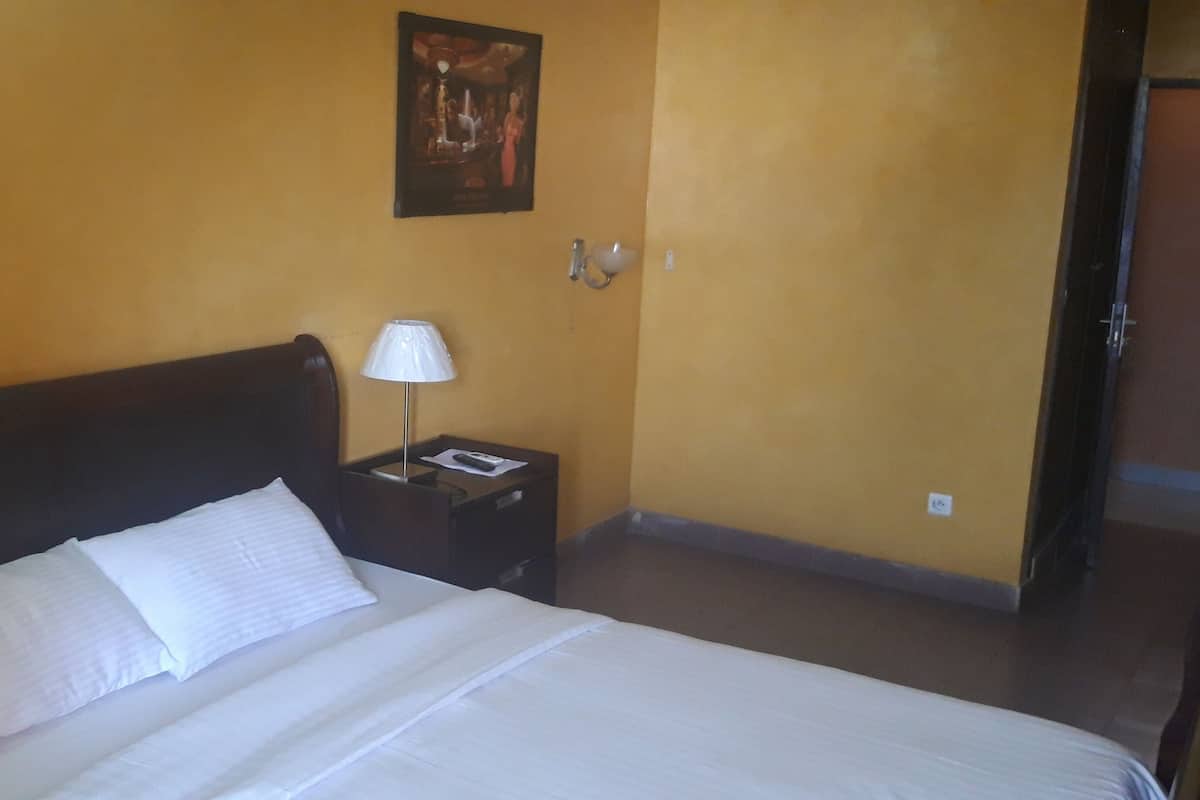 A hotel room with a bed, a nightstand with a lamp, and a wall-mounted picture.