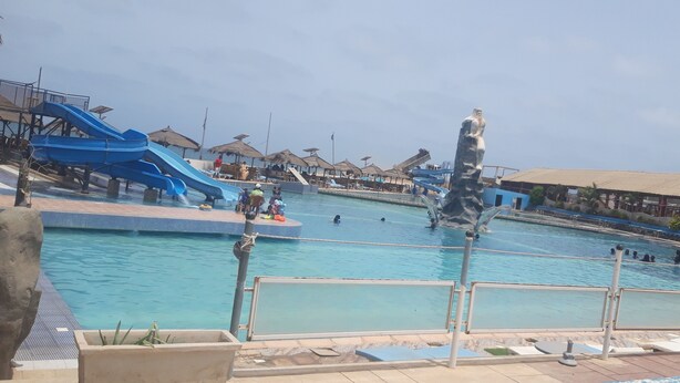 Une grande piscine extérieure dotée de plusieurs toboggans et ornée d’une statue.