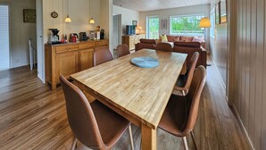 A spacious dining area with a wooden table and leather chairs, a kitchen with wooden cabinets, and a view of greenery outside. - Nice home in Vesterøy with WiFi (Vesterøy)