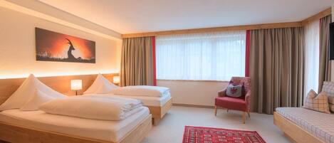 A hotel room with two beds, a red armchair, a red patterned rug, and a painting on the wall.