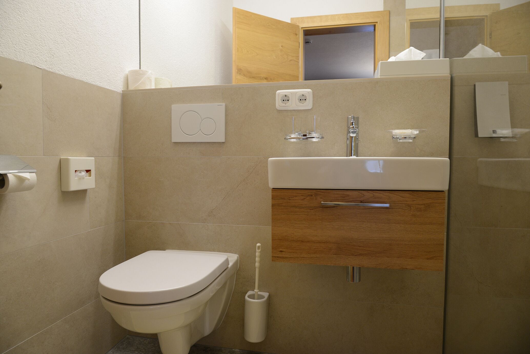 Ein modernes Badezimmer mit Toilette, Waschbecken und Spiegel.
